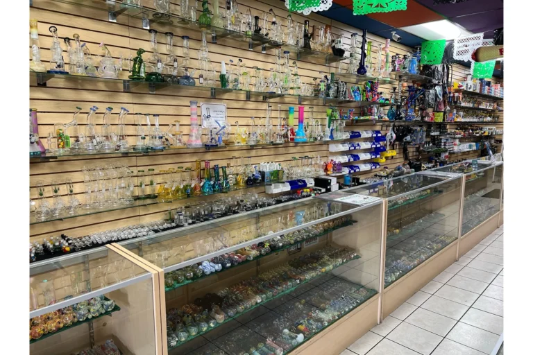 Close-up view of the glass wall at Fox Plaza Smoke Shop, showcasing bongs, pipes, and one-hitters.