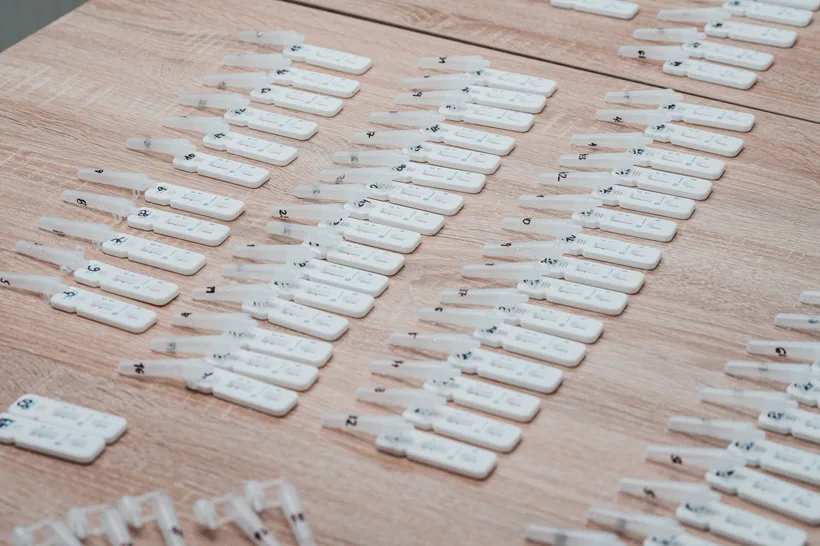 Dozens of small lateral-flow test cassettes arranged in neat rows on a wooden table at El Paso Smoke Shops