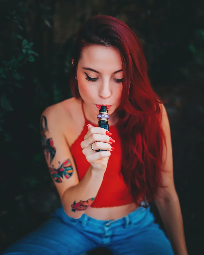 Una mano sosteniendo un vape desechable chiquito y sencillo estilo barra contra luces cálidas desenfocadas en El Paso Smoke Shops