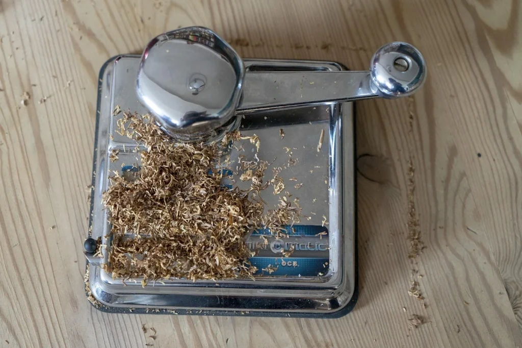 Chrome manual cigarette injector machine loaded with loose tobacco on a wooden table at El Paso Smoke Shops