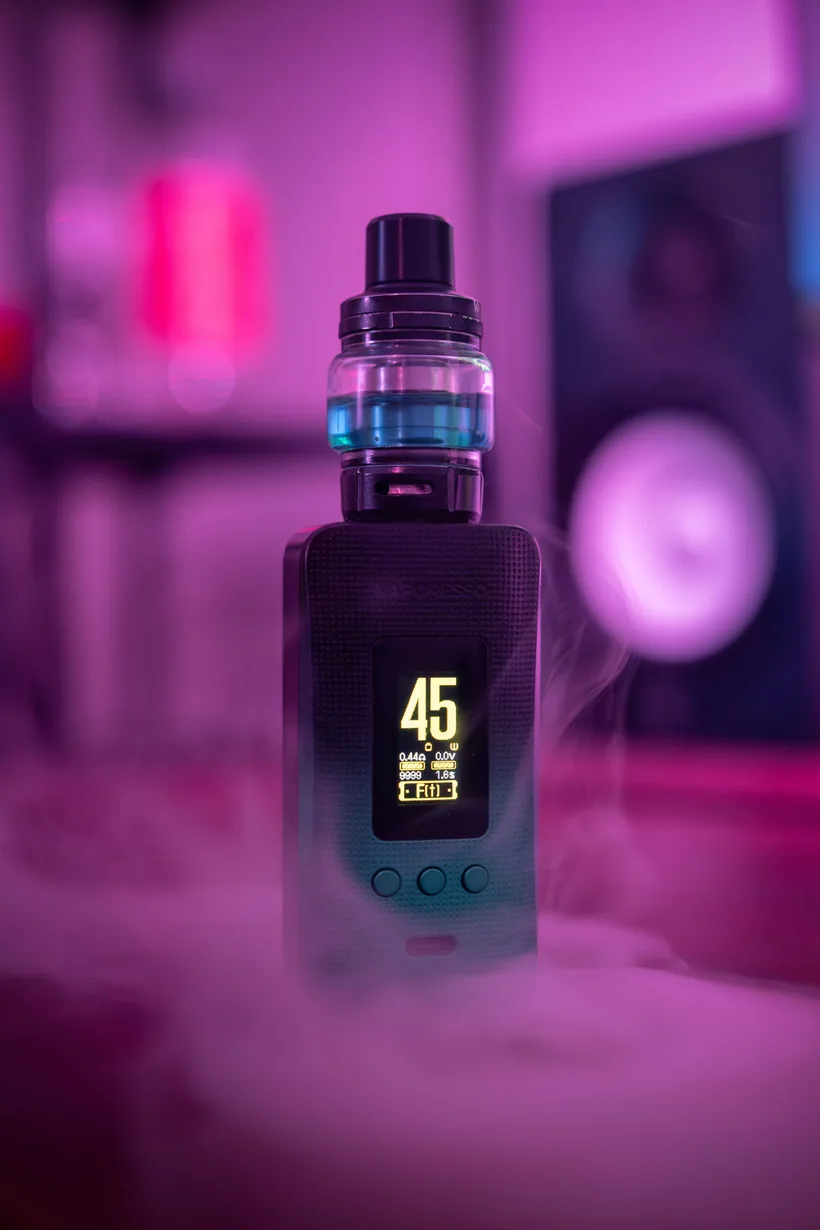 Vape device standing upright with a glowing digital display and a wisp of vapor rising from the mouthpiece, showing how a battery heats e-liquid into aerosol at El Paso Smoke Shops