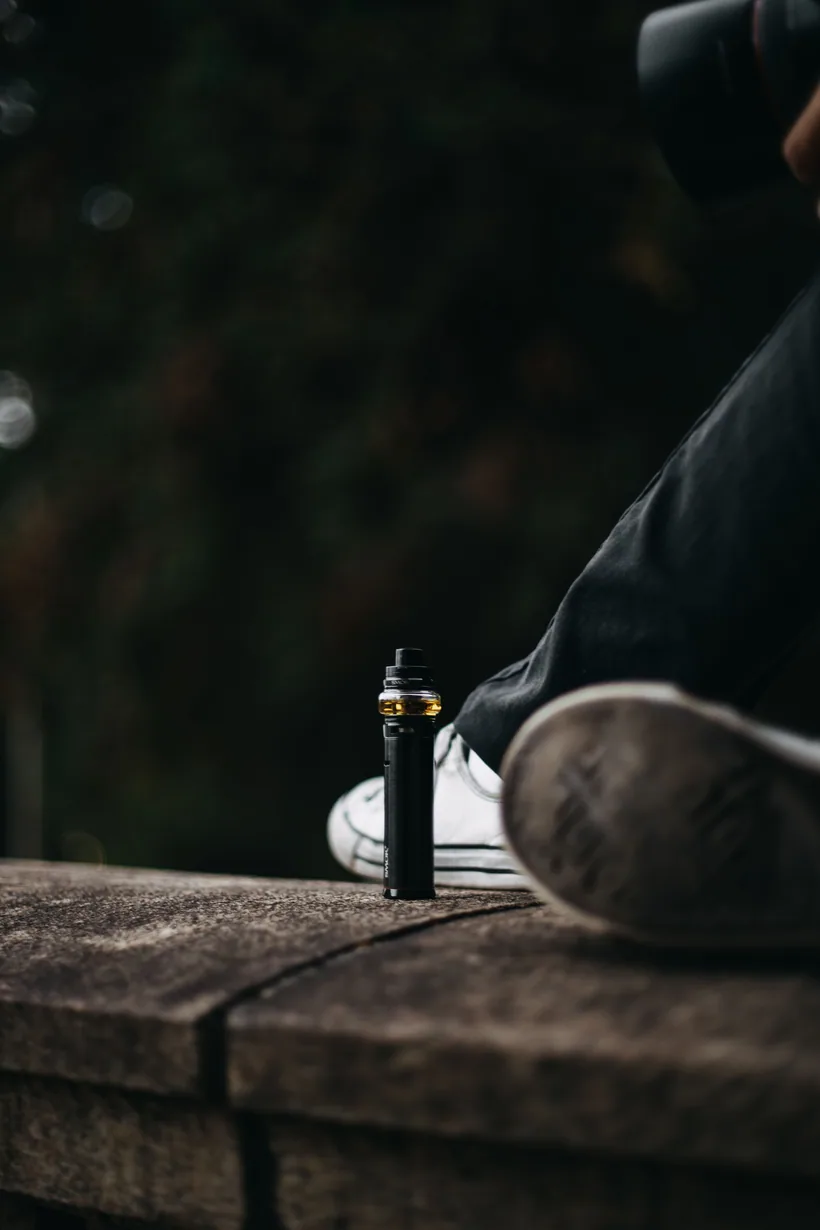 Slim portable vape pen standing on a stone ledge in an everyday outdoor setting, representing a compact device size that fits a daily carry at El Paso Smoke Shops