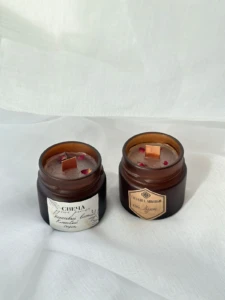 Amber glass scented jar candle with a printed label resting in a wooden bowl with botanicals at El Paso Smoke Shops