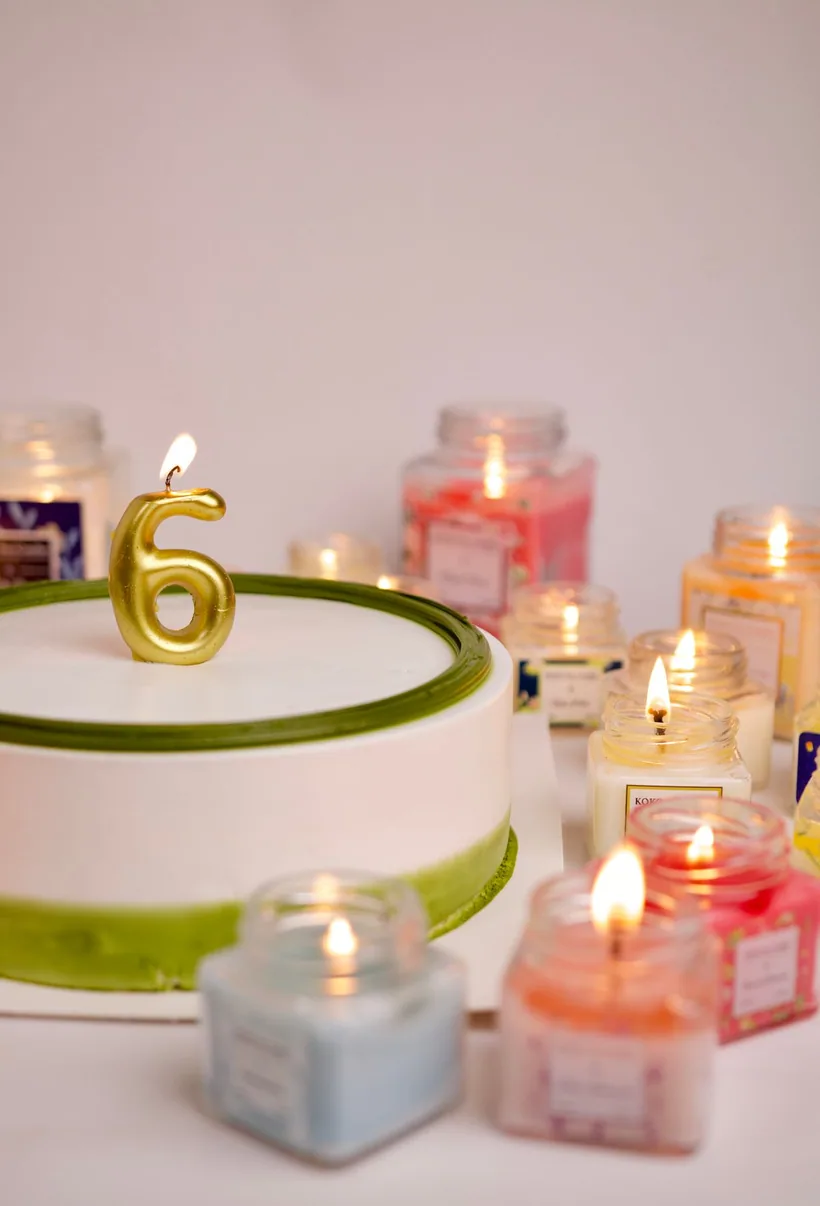 A pair of labeled amber scented jar candles with wood wicks set against soft white fabric at El Paso Smoke Shops
