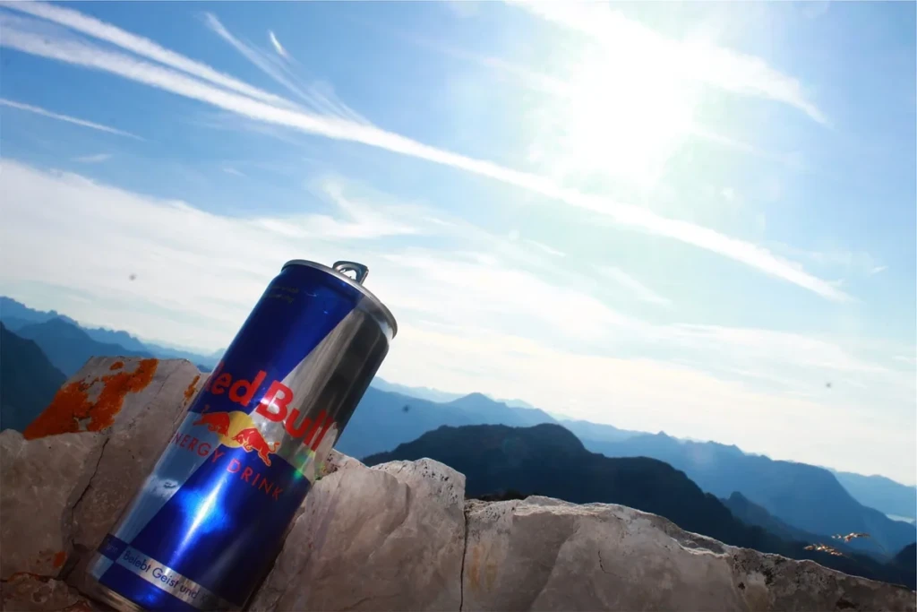 A tall energy drink can labeled "Energy Drink" resting on a sunlit rock against a bright sky, evoking the canned energy drinks at El Paso Smoke Shops