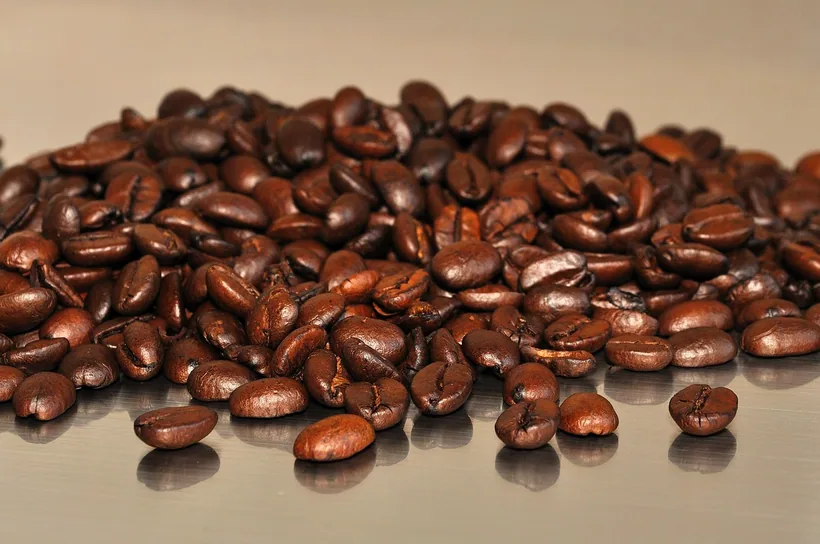 A close-up pile of glossy roasted coffee beans, representing natural caffeine from coffee-bean extract at El Paso Smoke Shops