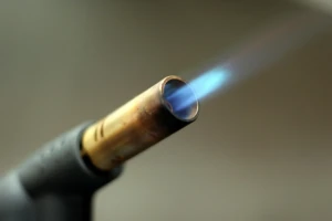 Handheld butane torch nozzle firing a focused blue jet flame at El Paso Smoke Shops