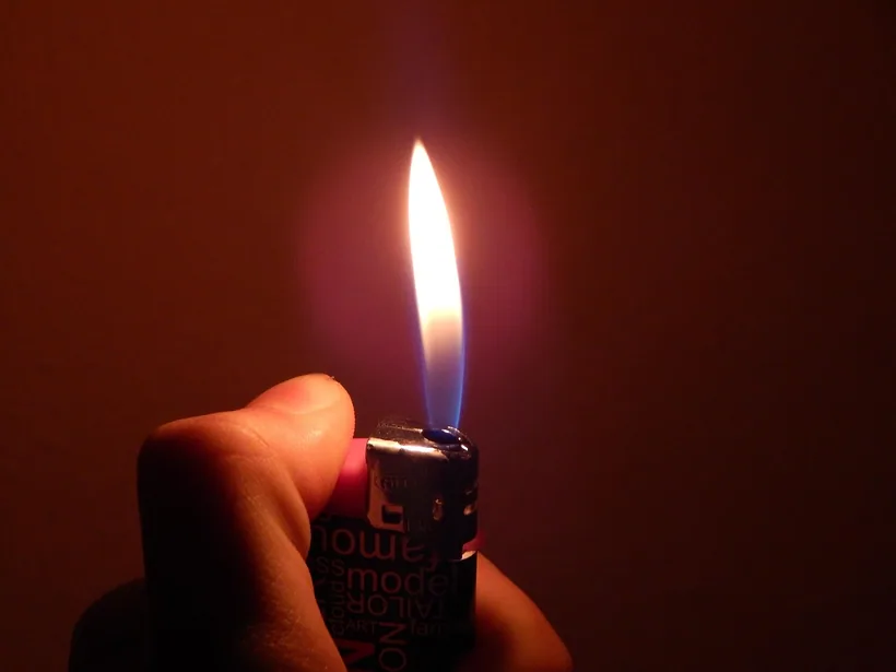 Mano sosteniendo un encendedor de bolsillo de butano rellenable prendido en El Paso Smoke Shops