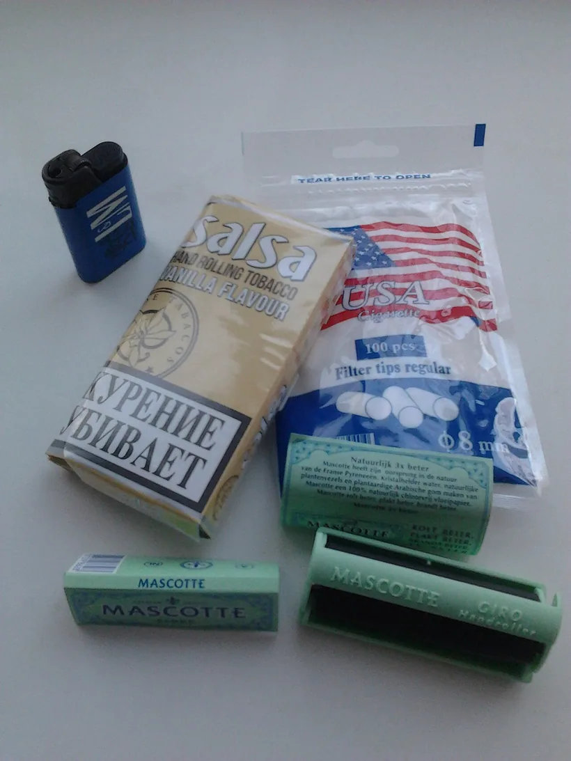 A green plastic hand-roller next to rolling papers, a pouch of rolling tobacco, and a pack of filter tips at El Paso Smoke Shops