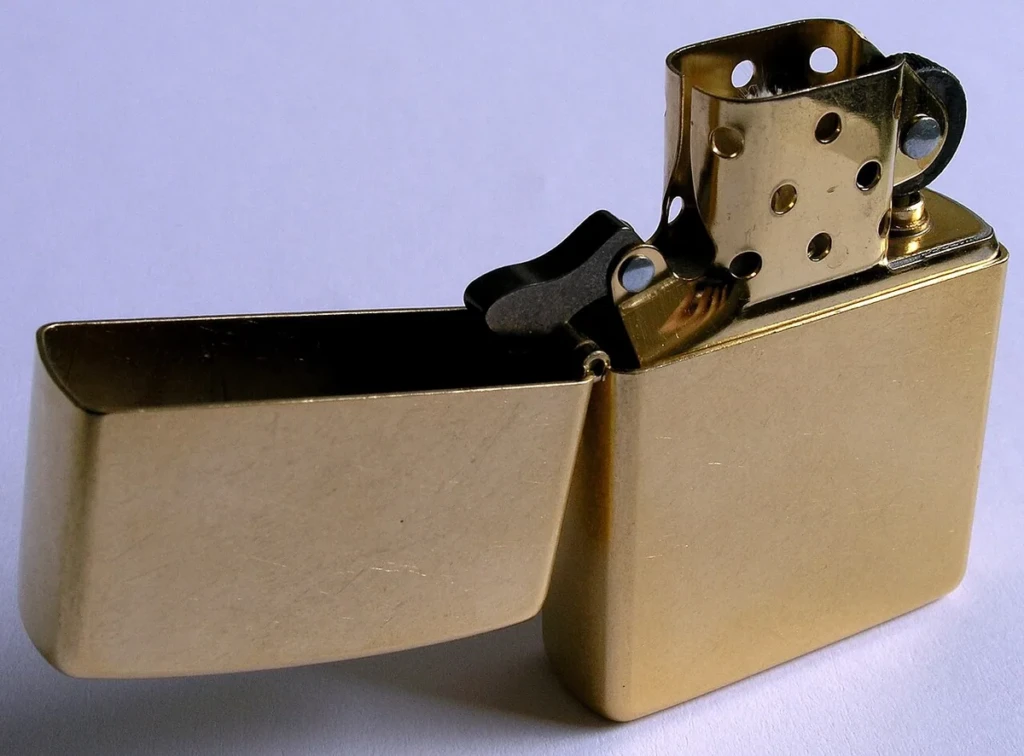 Solid-brass Zippo windproof lighter with the lid flipped open, showing the wick and chimney, at El Paso Smoke Shops