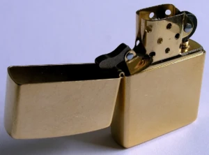Solid-brass Zippo windproof lighter with the lid flipped open, showing the wick and chimney, at El Paso Smoke Shops