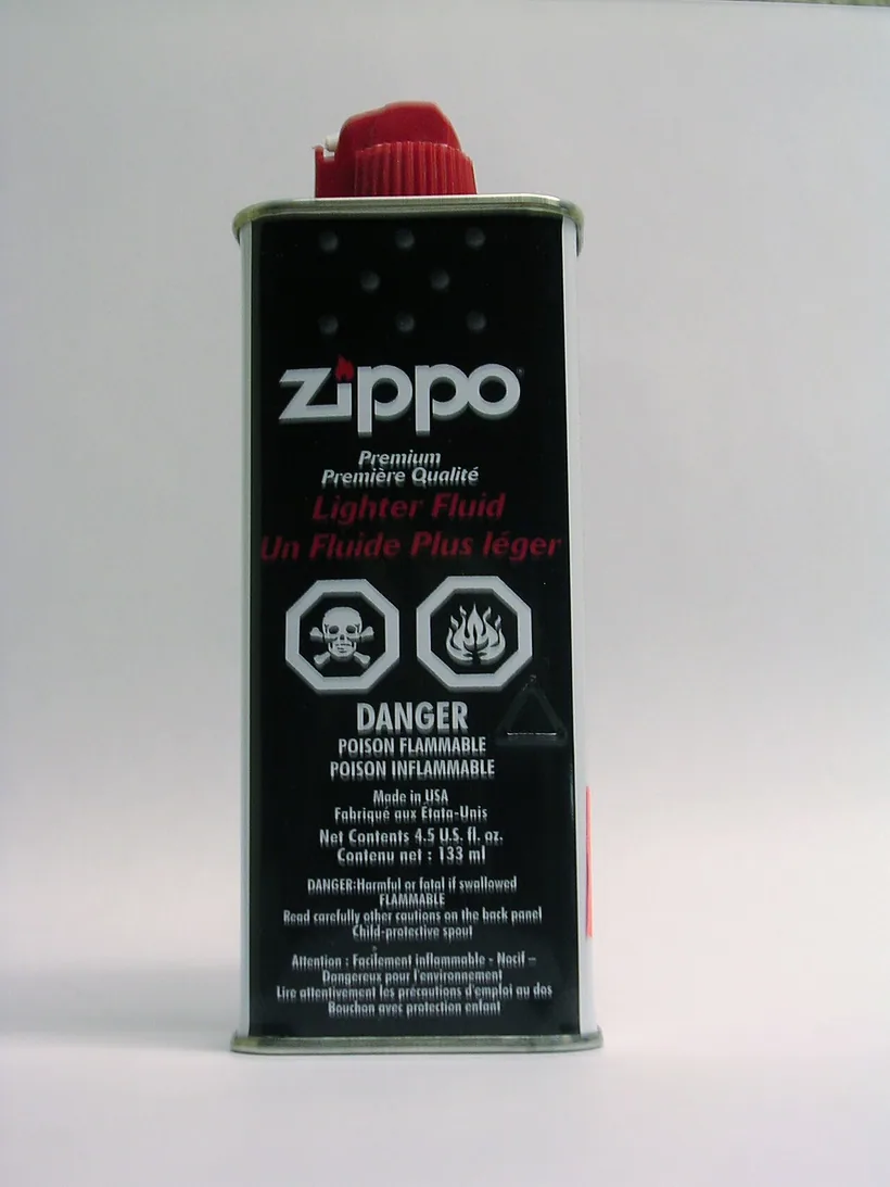 Una lata negra de Zippo Premium Lighter Fluid con su boquilla roja a prueba de niños sobre un fondo blanco, en El Paso Smoke Shops