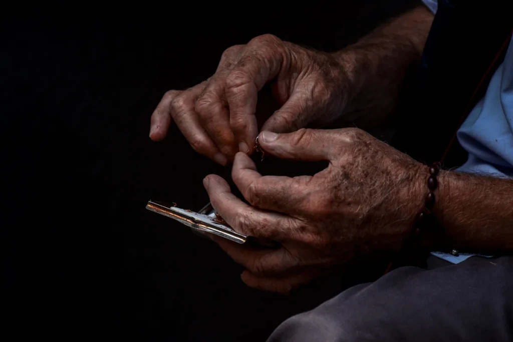 Adult hands using a metal cigarette rolling machine with loose tobacco to make roll-your-own cigarettes at El Paso Smoke Shops
