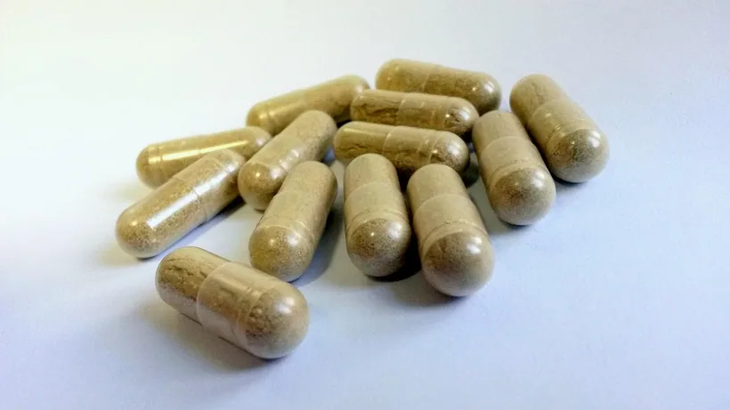 Cápsulas de gelatina de dos piezas rellenas de polvo herbal color canela sobre una superficie blanca en El Paso Smoke Shops