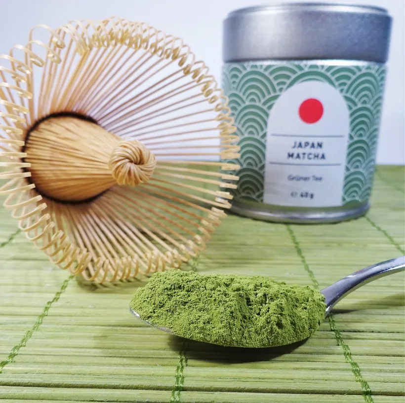 A spoon heaped with fine green botanical powder beside a whisk and tin, showing loose powder edibles can be made from at El Paso Smoke Shops