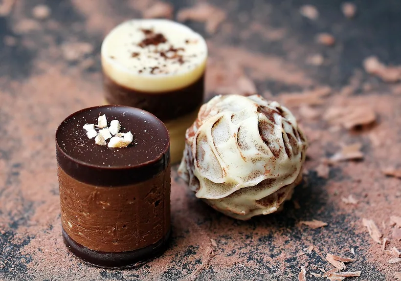 Three individually shaped chocolate pieces on a dark surface, showing the per-piece format of kratom chocolate edibles at El Paso Smoke Shops