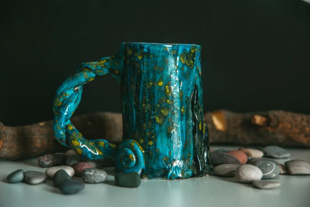 A distinctive handmade glazed ceramic mug with a twisted handle styled on a tabletop, illustrating the mug pipe and novelty ceramic style at El Paso Smoke Shops