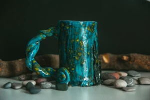 A distinctive handmade glazed ceramic mug with a twisted handle styled on a tabletop, illustrating the mug pipe and novelty ceramic style at El Paso Smoke Shops
