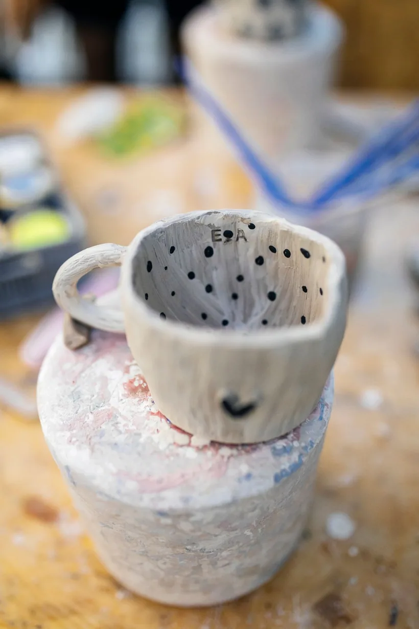 A handmade ceramic mug being shaped and detailed in a pottery studio, showing ceramic material and craftsmanship, at El Paso Smoke Shops