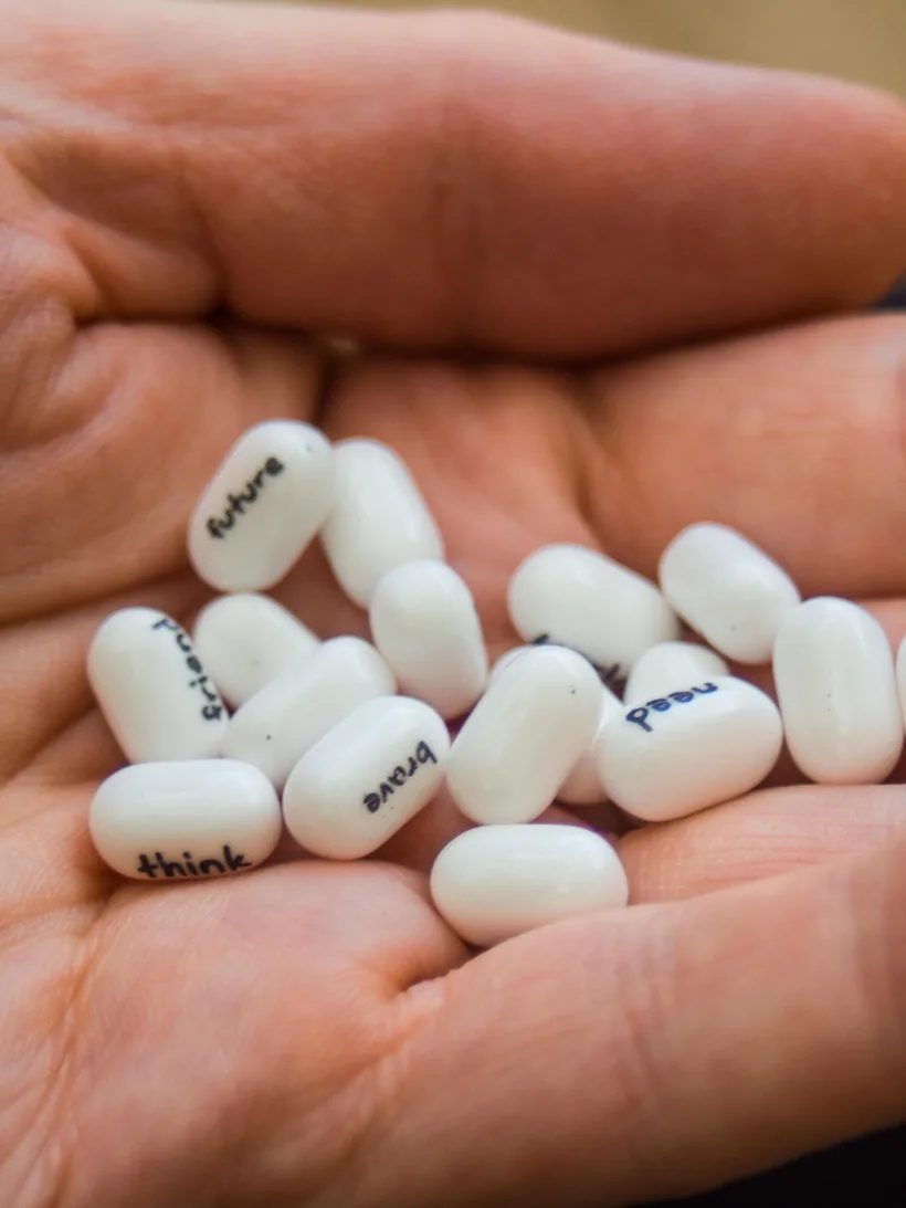 An adult's open hand holding several small white pressed lozenge pellets, ready to place one in the mouth, at El Paso Smoke Shops