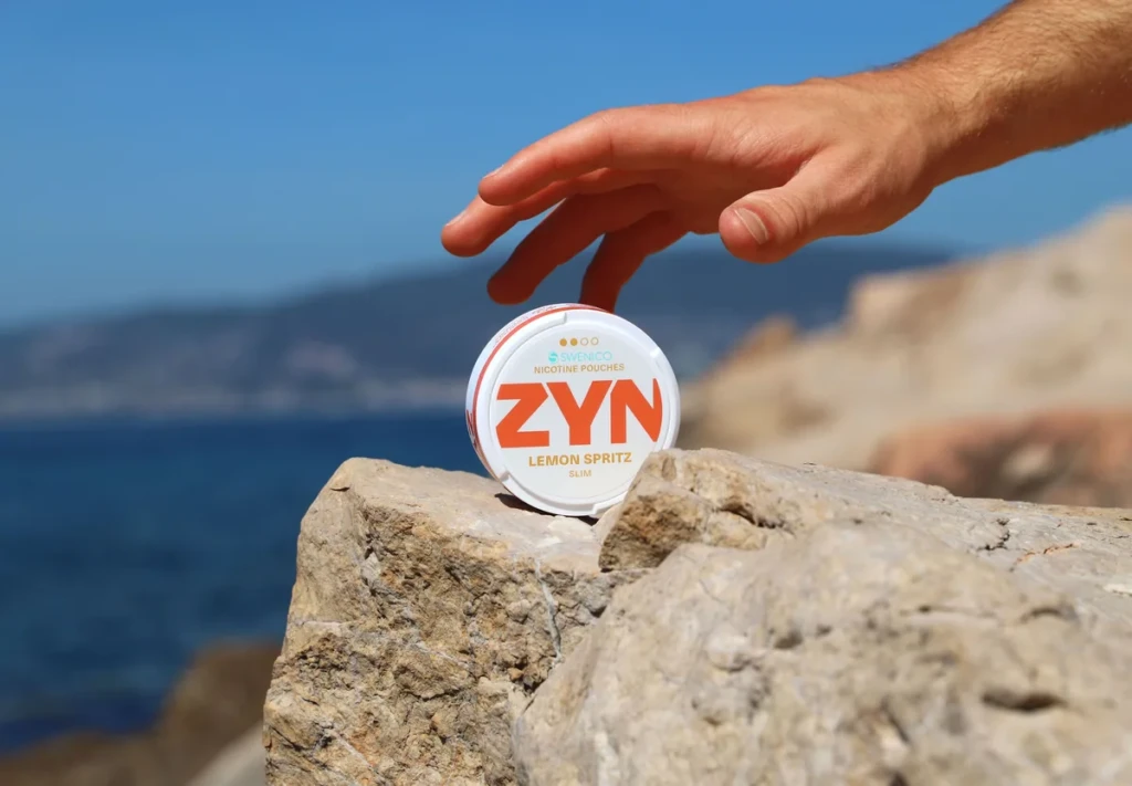 A ZYN nicotine pouches can in Lemon Spritz Slim resting on a sunlit seaside rock at El Paso Smoke Shops