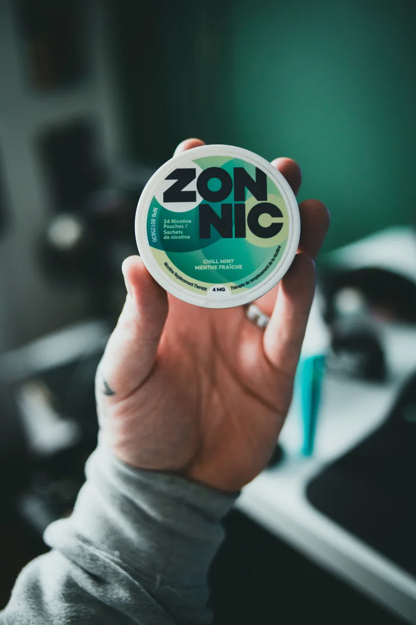 A hand holding a branded tobacco-free Zonnic Chill Mint nicotine pouch can at El Paso Smoke Shops