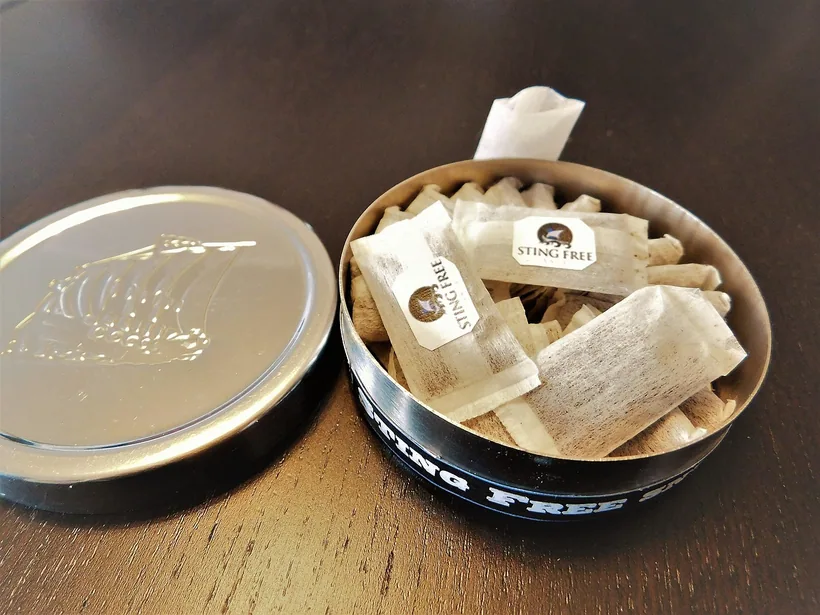 An open round nicotine pouch tin with its lid set beside it, the individual pouches clearly visible, at El Paso Smoke Shops