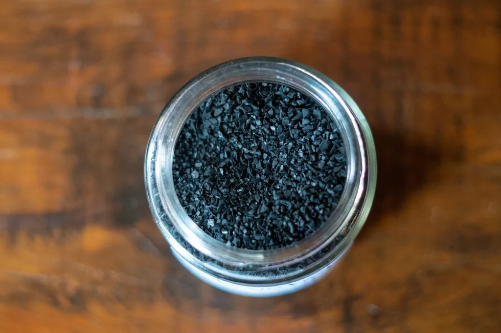 Close-up of activated carbon granules in a glass jar, the core filter media inside personal smoke filters, at El Paso Smoke Shops