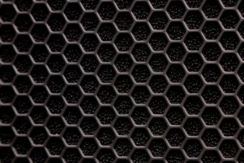 Macro view of a black activated-carbon honeycomb filter grid showing its hexagonal odor-trapping cells, at El Paso Smoke Shops