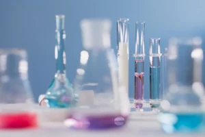 Glass test tubes holding vividly colored purple, blue, and red liquid in a bright laboratory setting at El Paso Smoke Shops