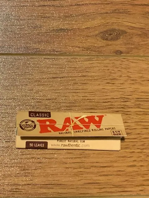 A booklet of RAW Classic natural unrefined 1 1/4 hemp rolling papers resting on wood at El Paso Smoke Shops