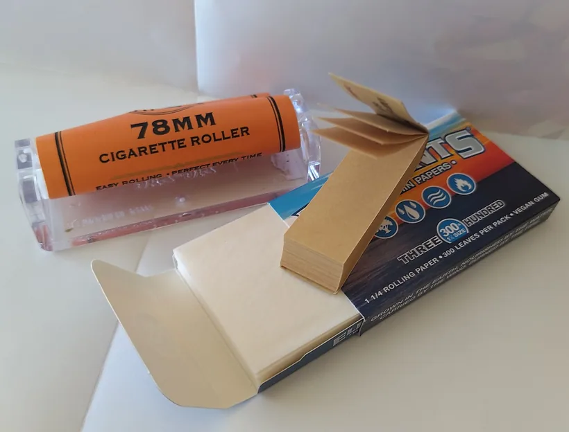 An open Elements 1 1/4 rolling paper booklet beside a 78mm cigarette roller and a stack of filter tips at El Paso Smoke Shops