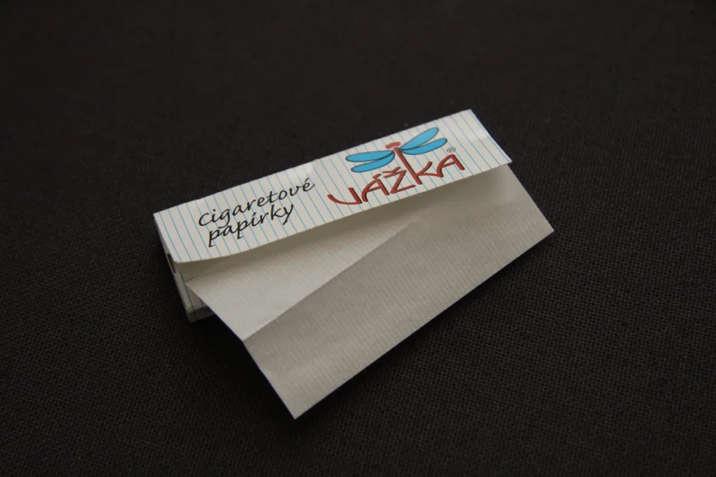 An open booklet of cigarette rolling papers with a single leaf pulled out, photographed on a dark background at El Paso Smoke Shops