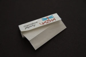 An open booklet of cigarette rolling papers with a single leaf pulled out, photographed on a dark background at El Paso Smoke Shops
