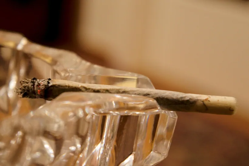 A hand-rolled cigarette resting on a glass ashtray with a rolled-paper crutch tip visible at the mouth end at El Paso Smoke Shops