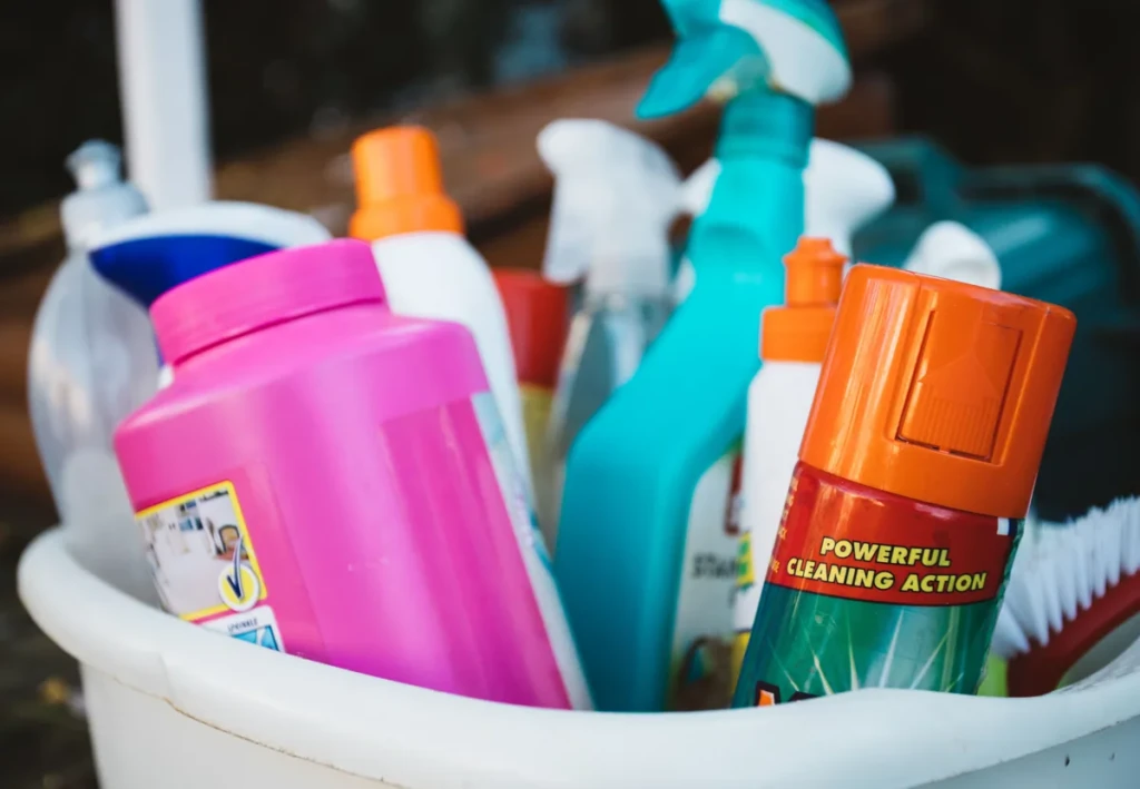 Bucket of assorted trigger spray bottles and odor-eliminating cleaning products, including a sprayer labeled for powerful cleaning action, at El Paso Smoke Shops
