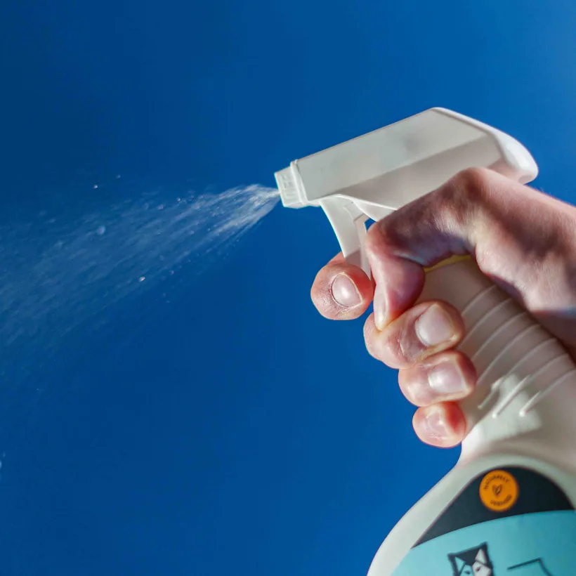 Hand actively spraying a trigger mist bottle with visible mist, clearing the air fast, at El Paso Smoke Shops