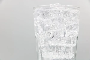 Tall glass of clear carbonated soda water filled with ice and rising bubbles on a clean studio background at El Paso Smoke Shops