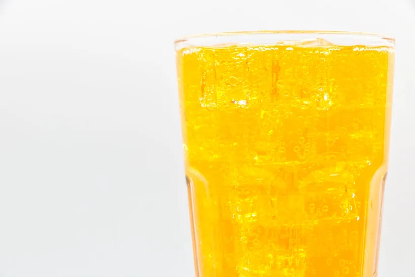 Glass of bright orange flavored fizzy soda with carbonation on a light background at El Paso Smoke Shops
